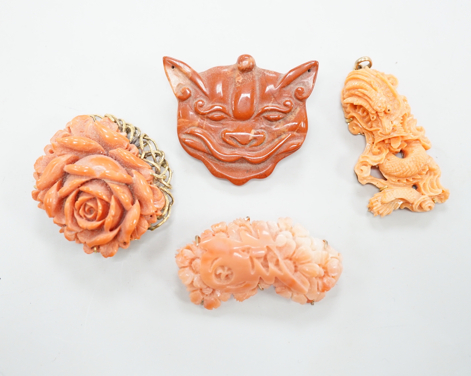 A Chinese yellow metal mounted coral pendant, carved with a grotesque beast, 52mm, a 585 mounted coral brooch, carved with roses and two other items.